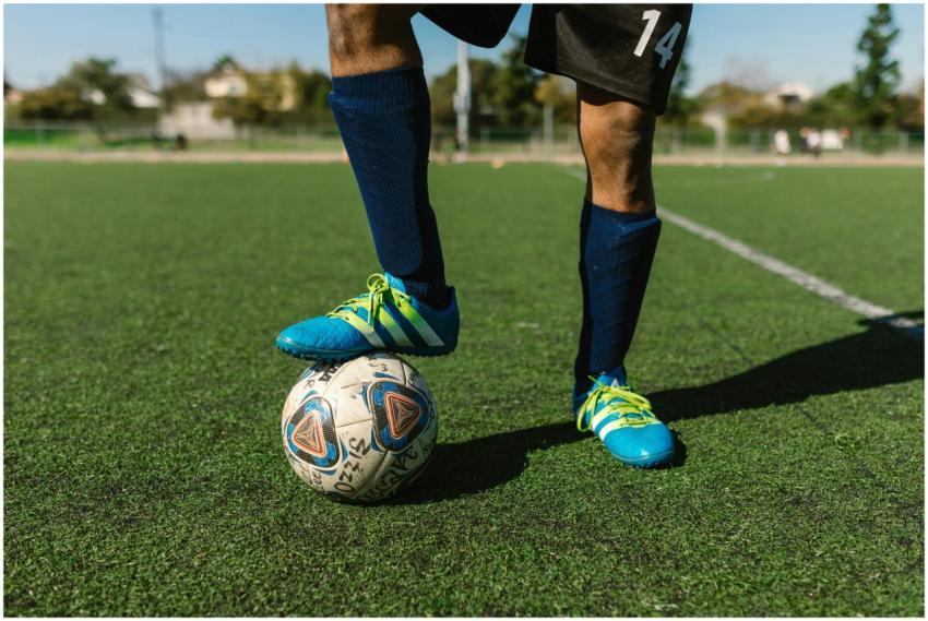 Close-up of a soccer player with a ball on a green