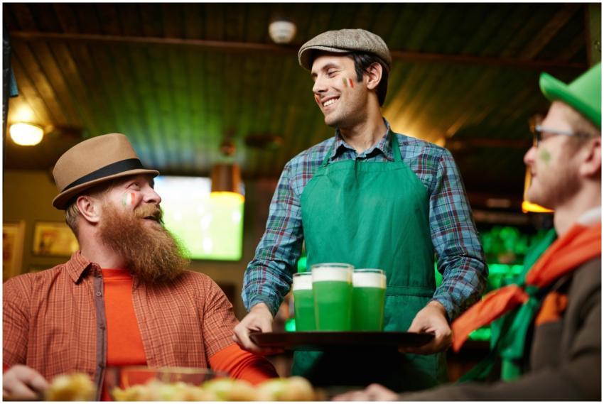Friends enjoy green beer at a pub, celebrating St.