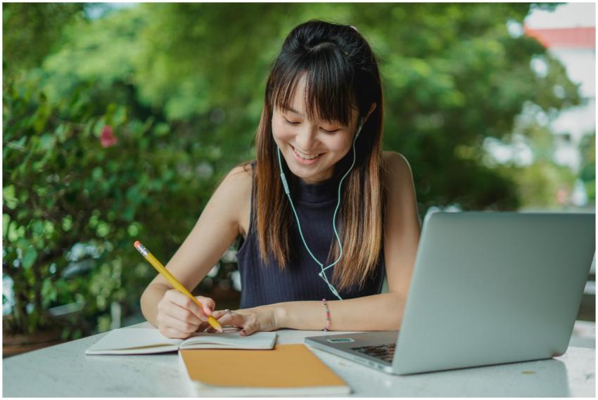 Positive young Asian female student with earphones