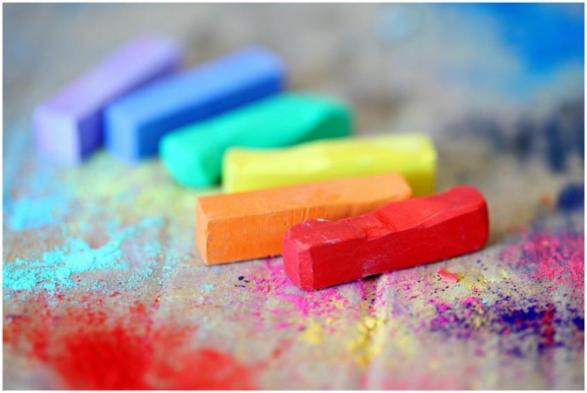 Vibrant pastel chalks on colorful splattered canva