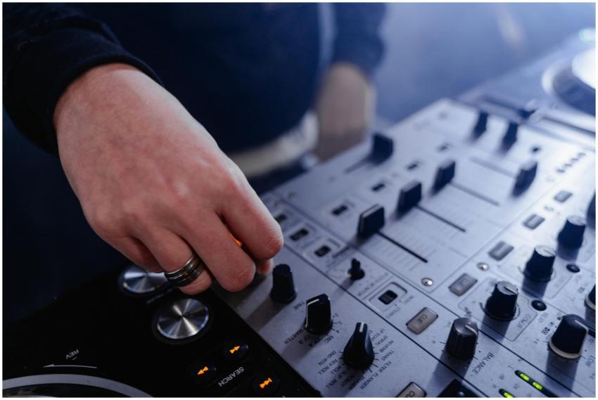 Hand adjusting controls on a DJ mixer at an indoor