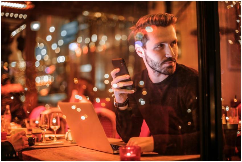 A stylish man at a chic Budapest cafe, using a sma