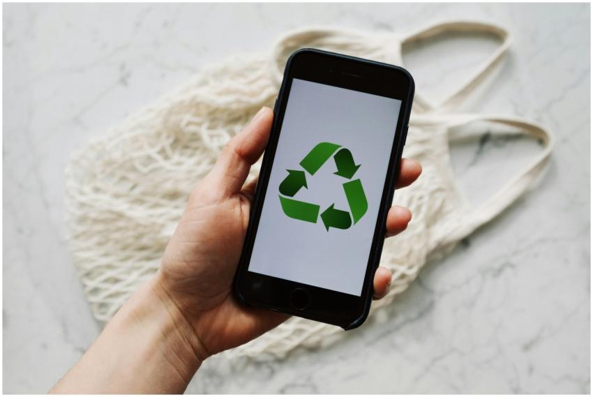 A hand holding a smartphone with a recycle symbol,