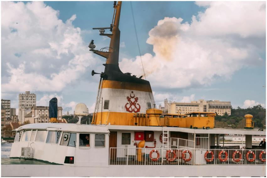A vibrant ferry releases smoke as it sails by a ci