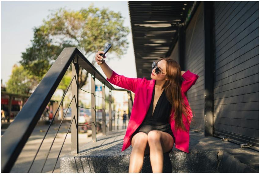 Trendy young woman in pink blazer taking a selfie