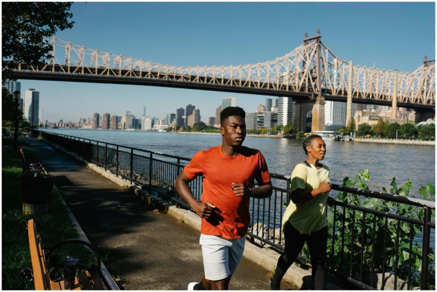 Dynamic shot of a couple jogging by a city river w