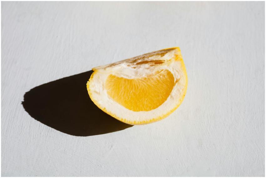 A fresh lemon half casting a shadow on a bright ba