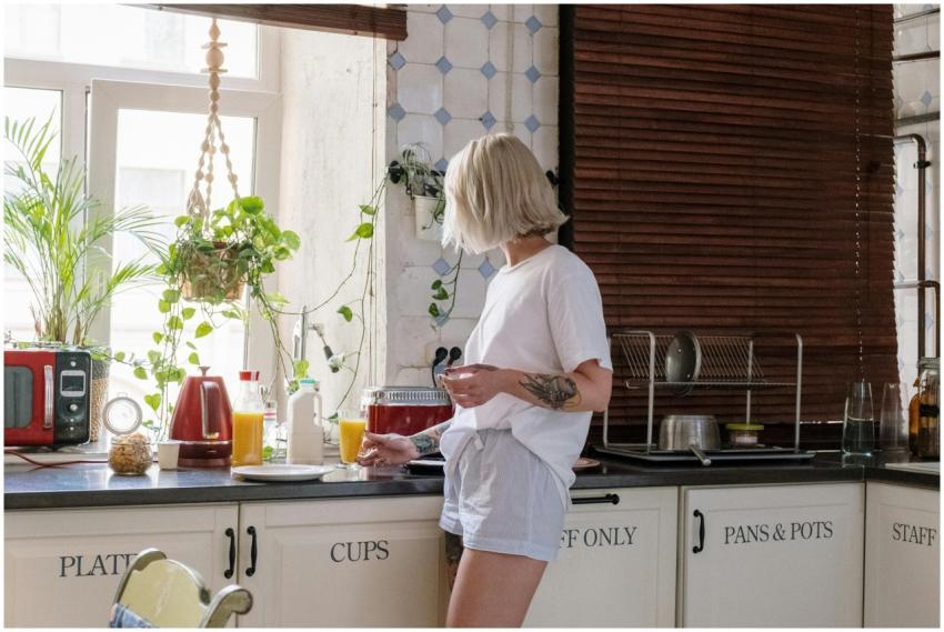 Woman with a tattoo preparing orange juice in a br