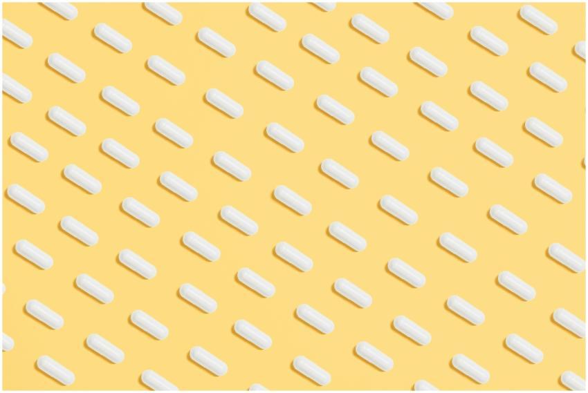 Pattern of white capsules on a bright yellow surfa