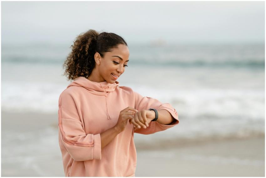 Smiling woman in a pink hoodie checks her smartwat