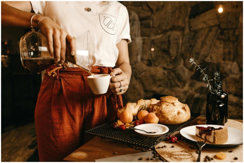 A woman pours coffee into a cup, surrounded by fre