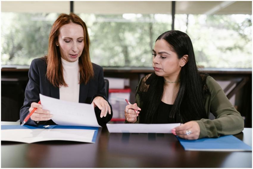 Two professional women reviewing documents in a we