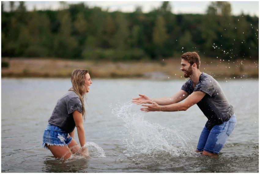 A joyful young couple playing and splashing water