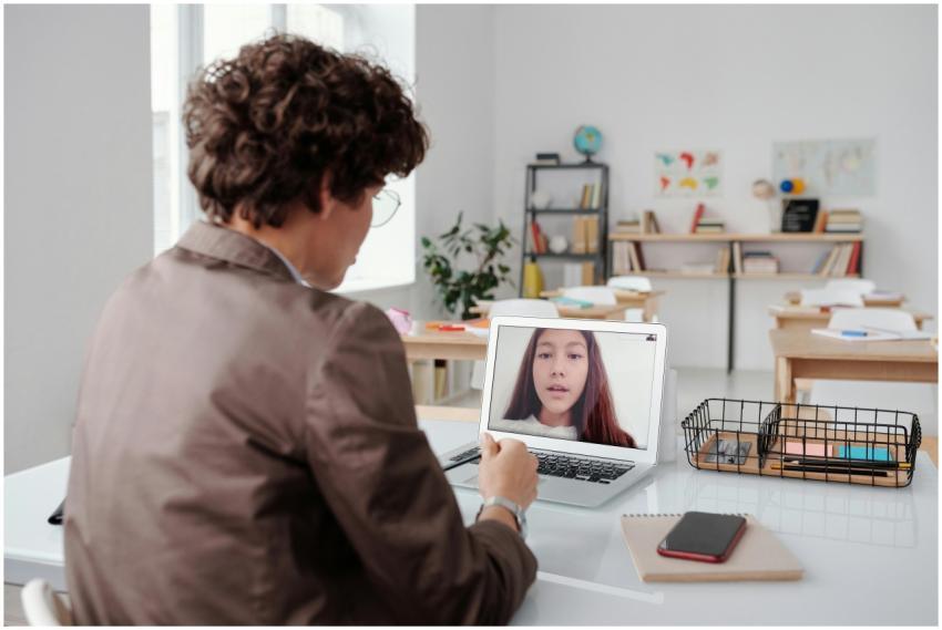 A teacher engages in an online class from an empty