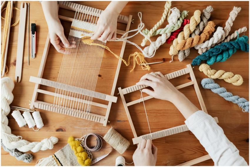 Hands weave yarn on looms in a vibrant workshop, s
