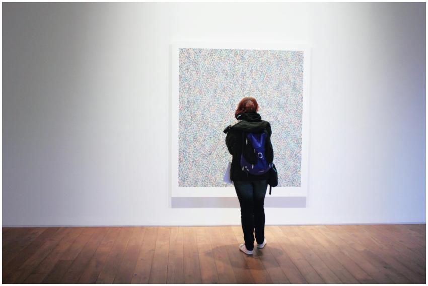 A woman with a backpack observes a colorful painti