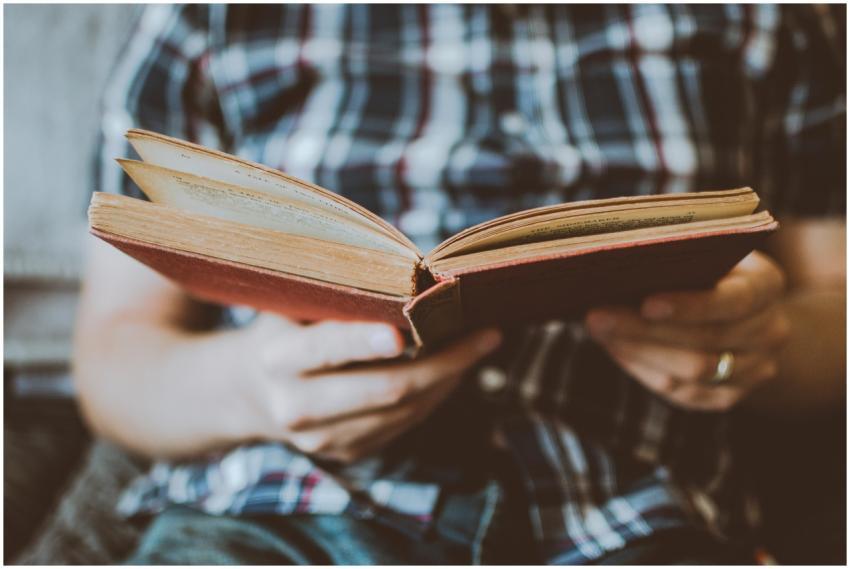 Close-up of hands holding and reading an antique b