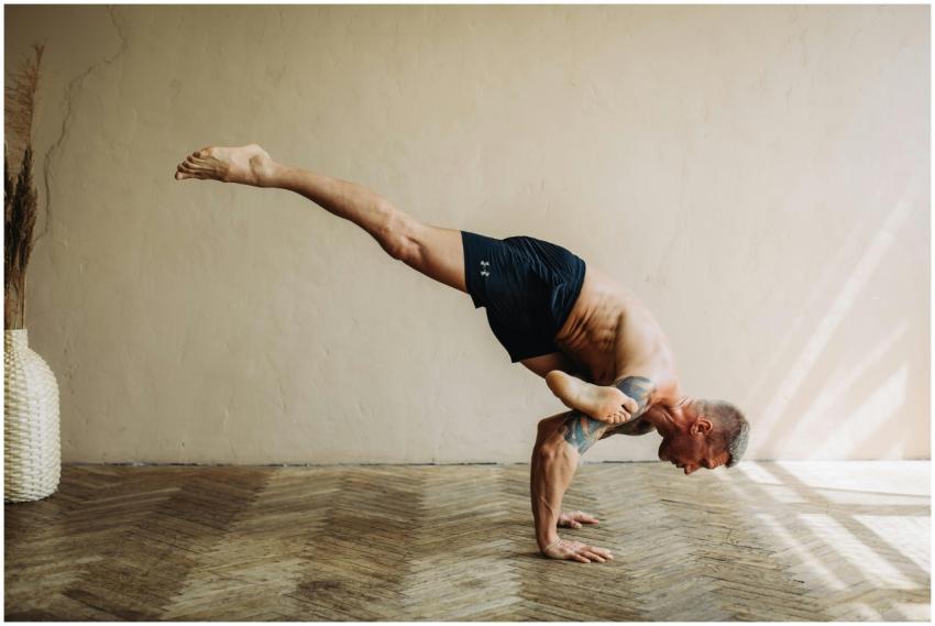 A shirtless man demonstrates advanced yoga balance