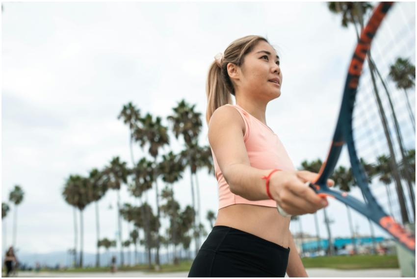 A woman in activewear playing tennis outdoors on a