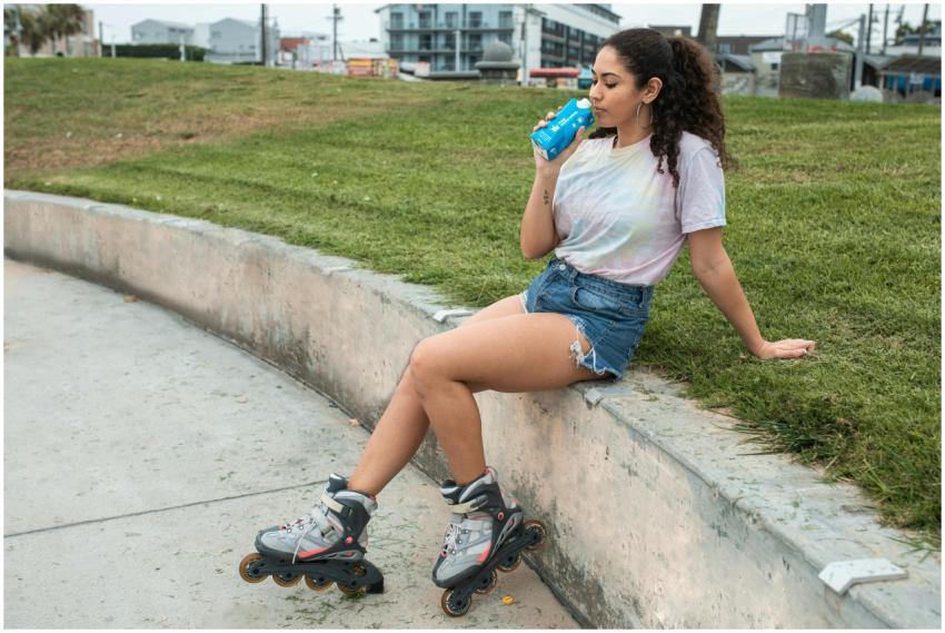 Woman sitting on concrete railing wearing rollerbl