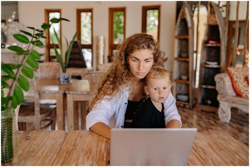 Mother and child sit at a wooden table with a lapt