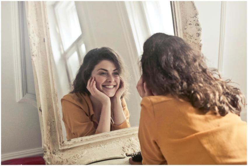 A cheerful woman smiles at her reflection in a vin