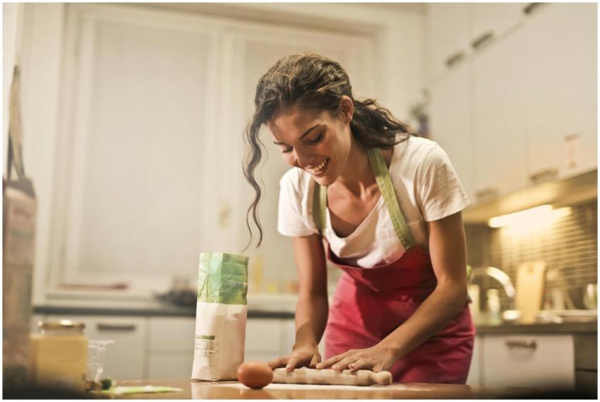 Smiling woman making dough at home, enjoying the b
