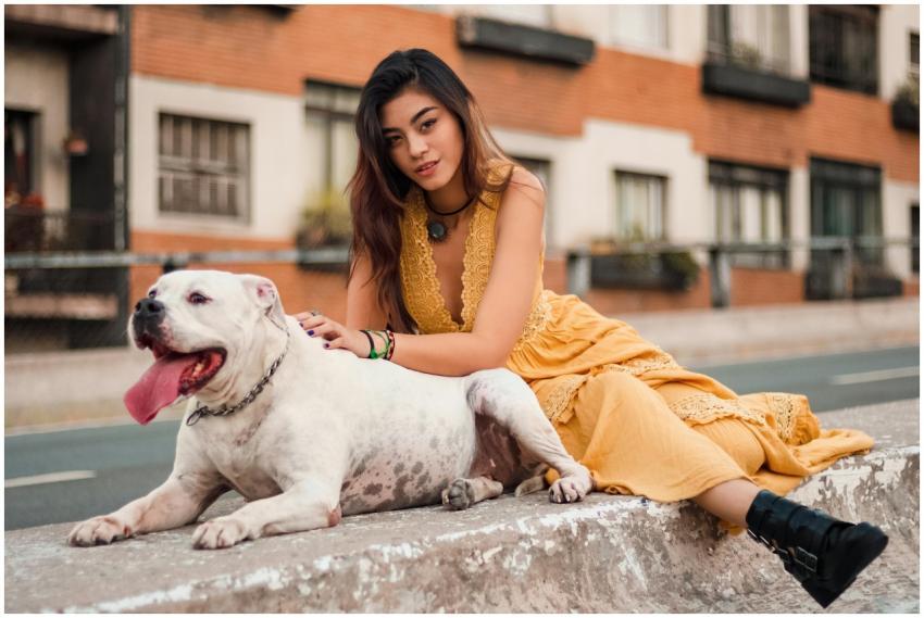 A woman in a yellow dress sits on a concrete barri