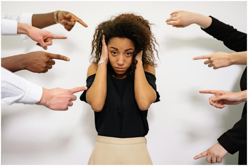 Stressed woman with hands on ears surrounded by po