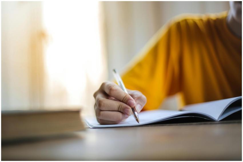 Close-up of a person writing in a notebook, symbol