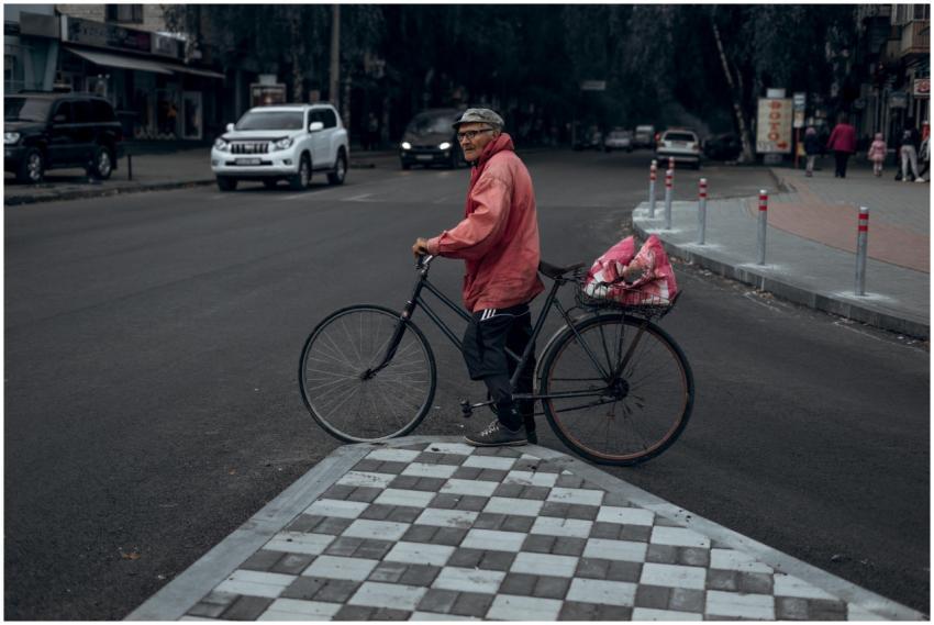 Man with bicycle stops at urban intersection on a
