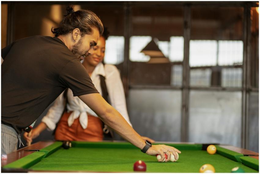 Two young adults enjoying a casual game of pool in