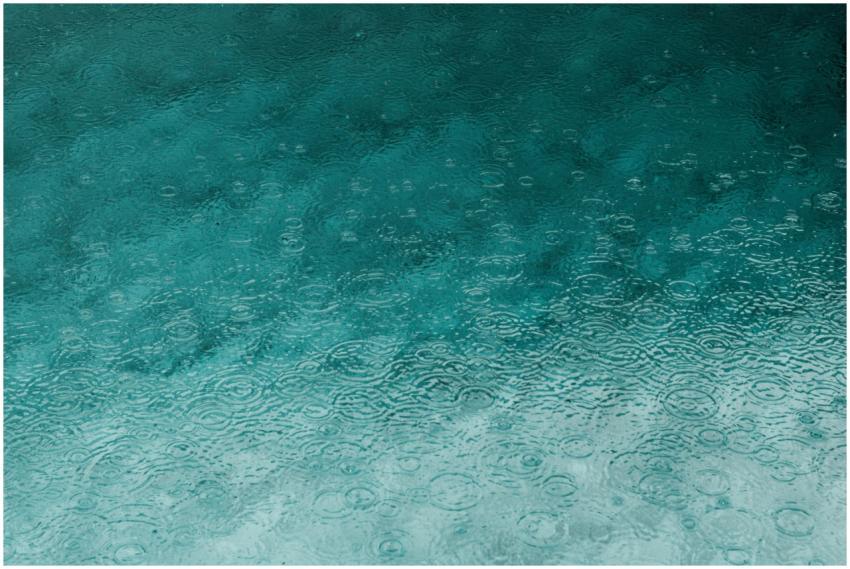 Serene teal water surface with ripples and raindro