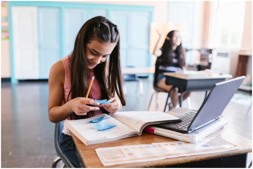 A young student in a classroom focusing on writing