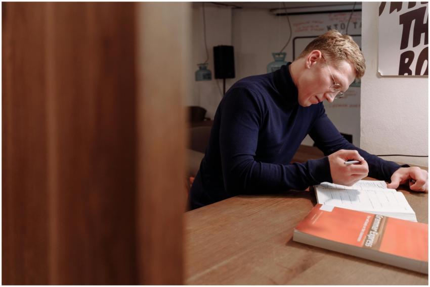 Caucasian man in blue sweater studies indoors, foc