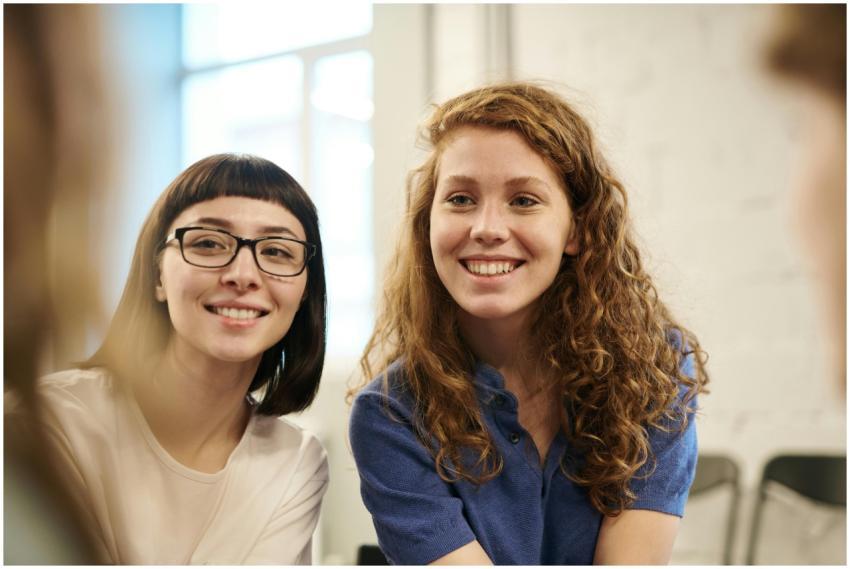Two smiling young women indoors, conveying friends