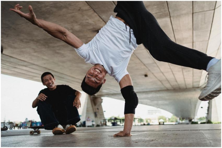 Two men enjoying skateboarding tricks under a conc