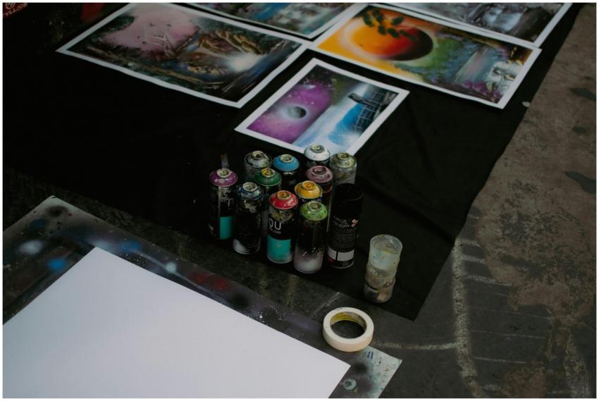 Spray cans and vibrant artworks laid on a canvas,