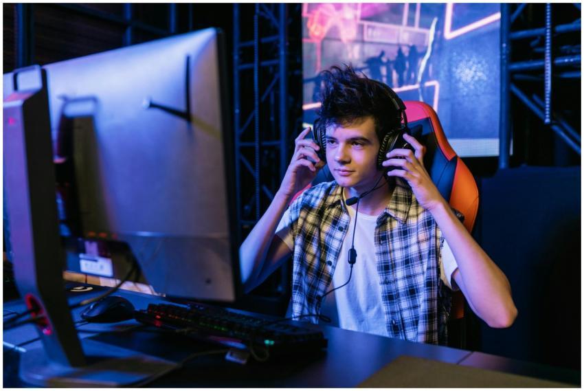 Teenage boy gaming at a computer station with head