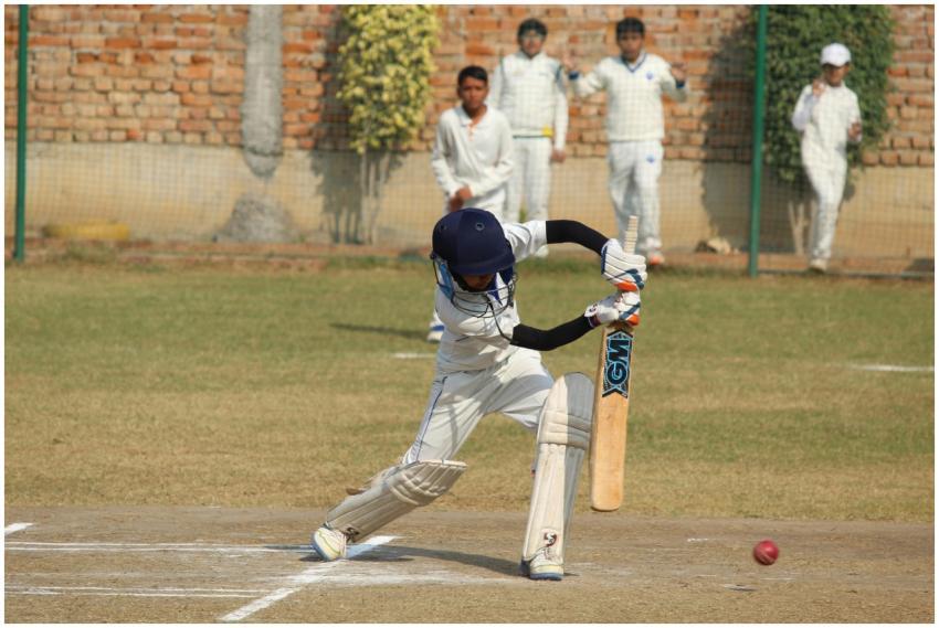 A young cricket player bats during a game on a sun