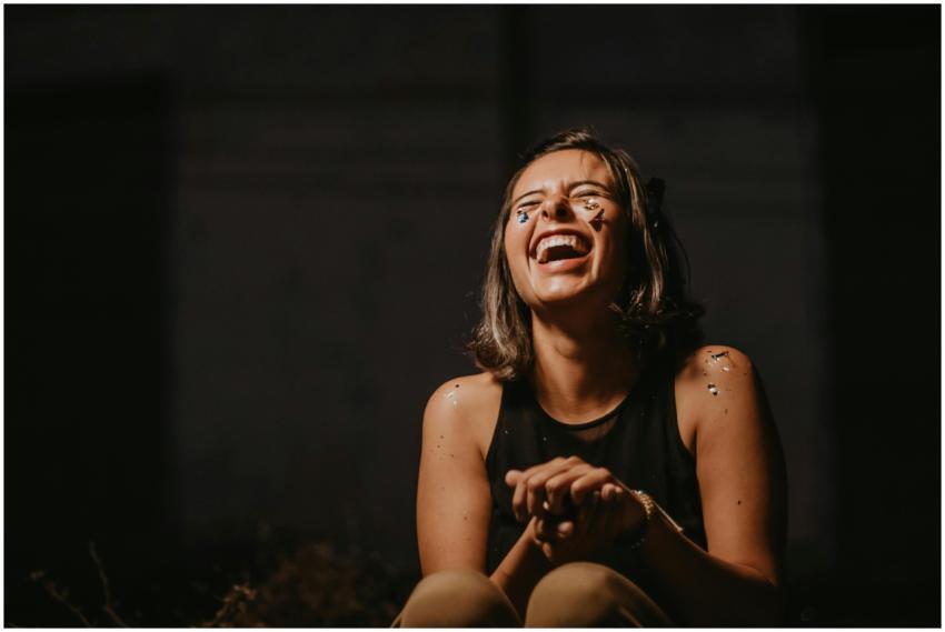 A joyful young woman laughing with confetti on a d
