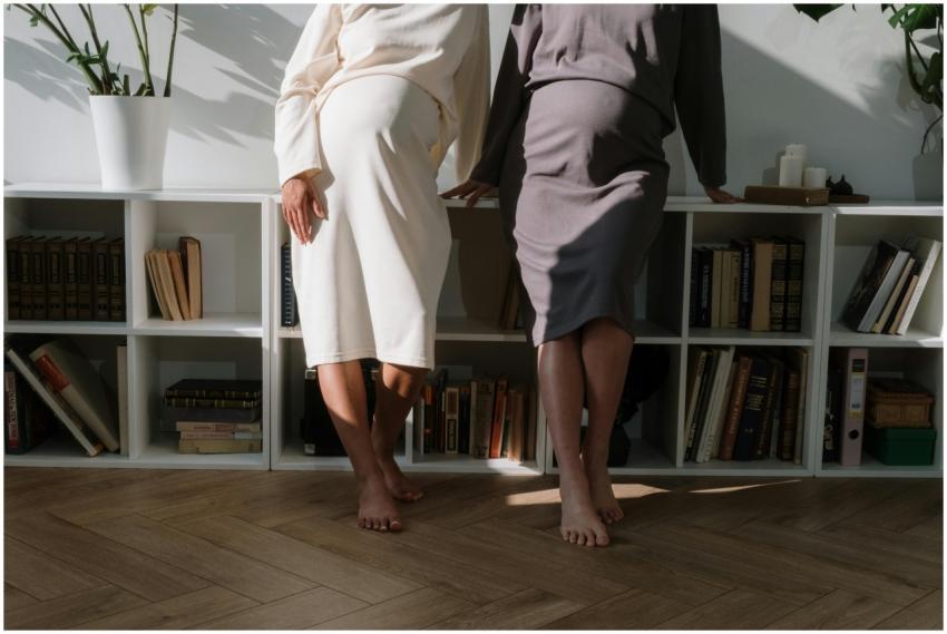 Two pregnant women in chic dresses pose indoors, e