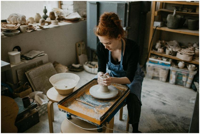 A skilled woman shapes a clay pot in an artistic p