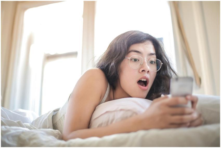 Young woman lying on bed, surprised by something o