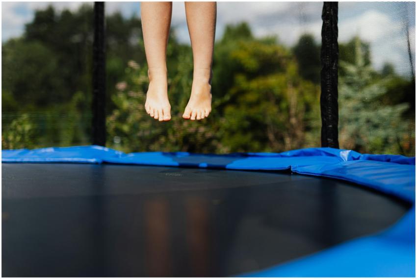A child's bare feet captured mid-jump on a trampol