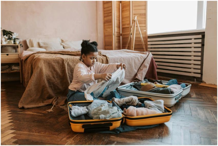 Young girl folding clothes and packing a suitcase