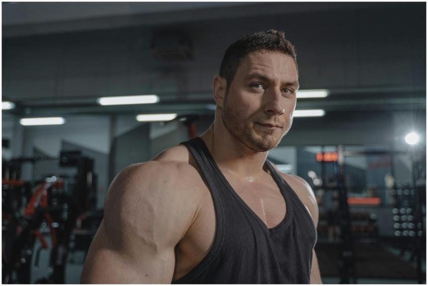 A muscular man in a black tank top posing confiden