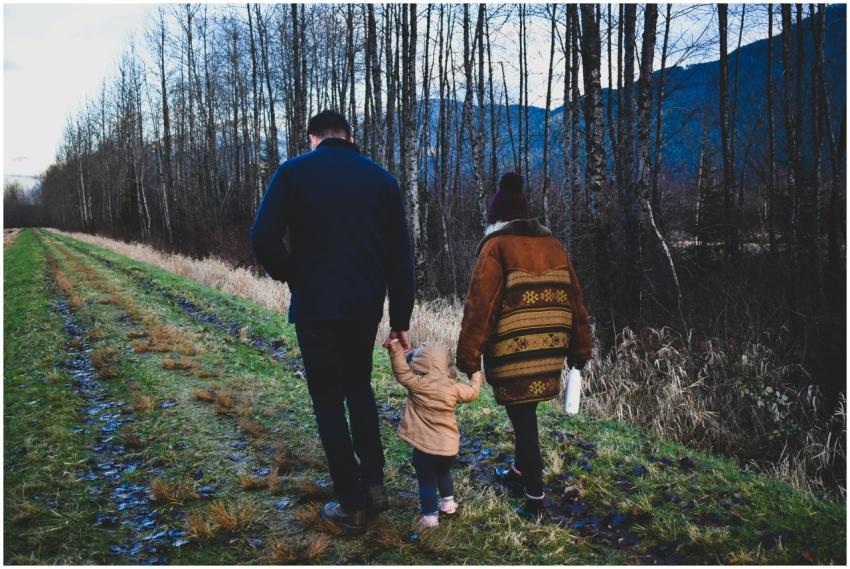 Family walking hand in hand along a forest path on