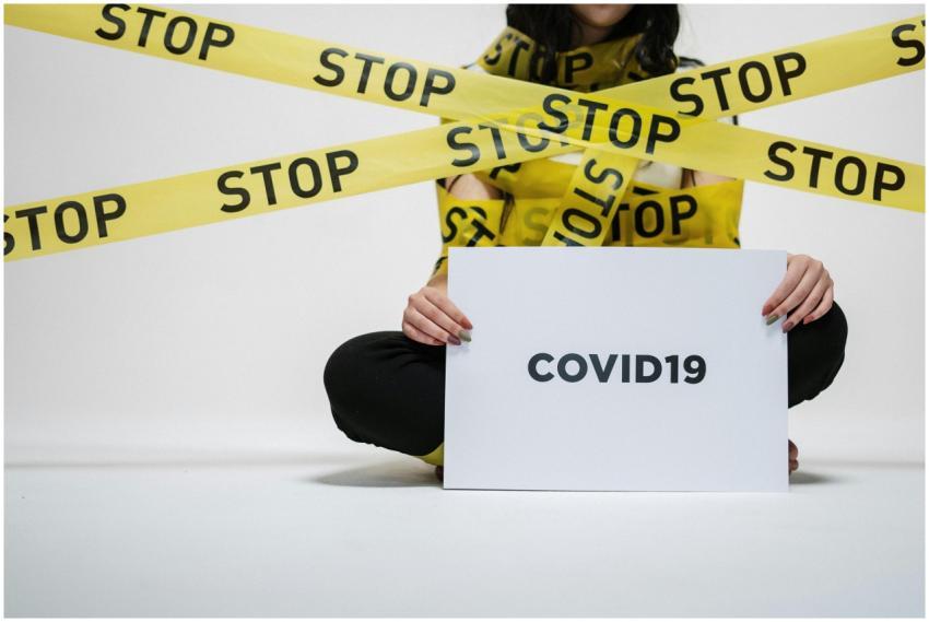 A woman holding a COVID-19 sign surrounded by yell