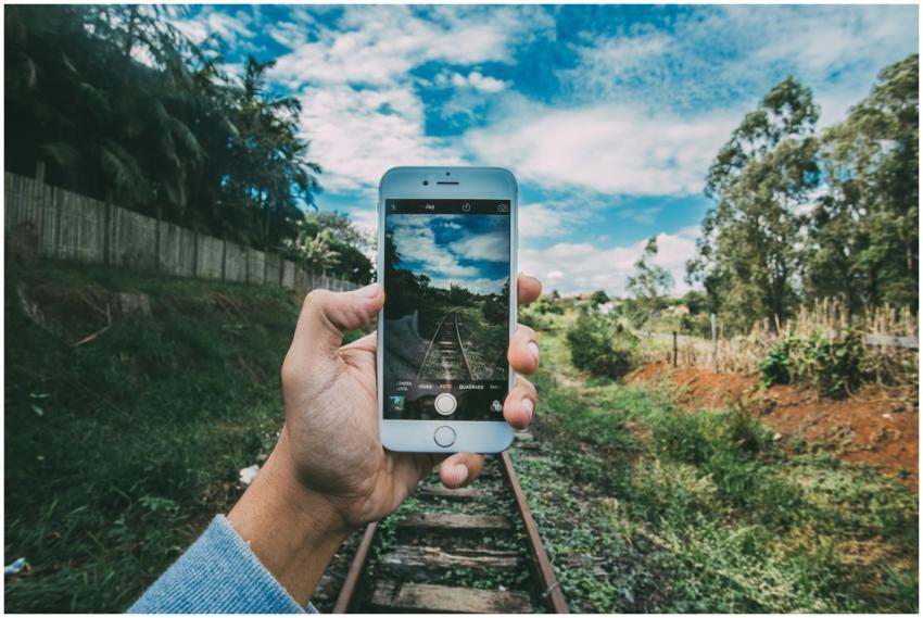 A person captures a scenic railway landscape using